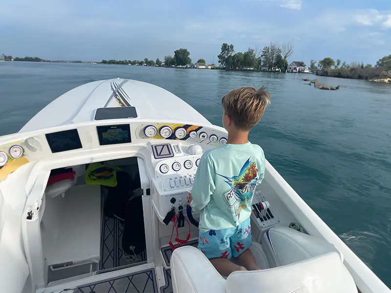 A little girl standing on the back of a boat.